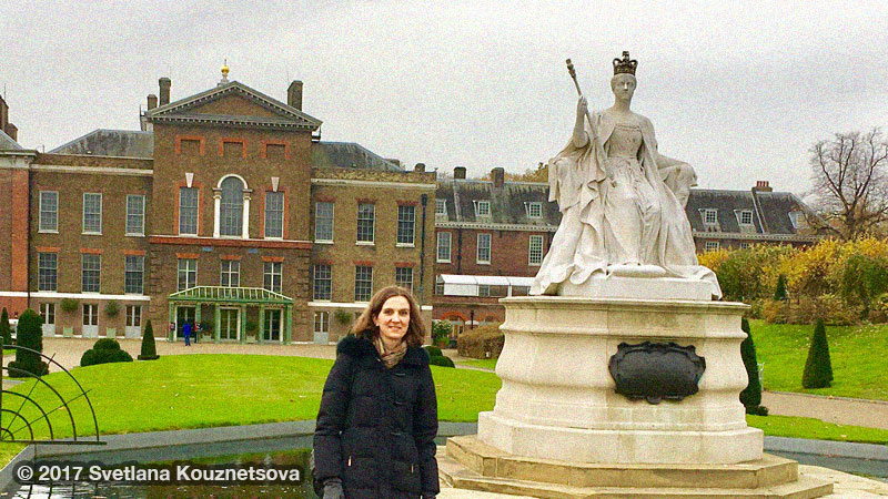 Svetlana standing in Kensington Gardens in front of Victoria statue and Kensington Palace.