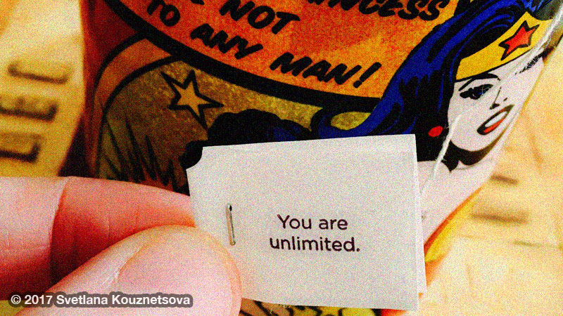 A mug with Wonder Woman and a hand in front holding a tea tag saying: You are unlimited.