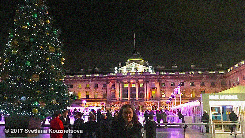 Svetlana standing in front of a Christmas tree and a skating rink at Somerset House in London